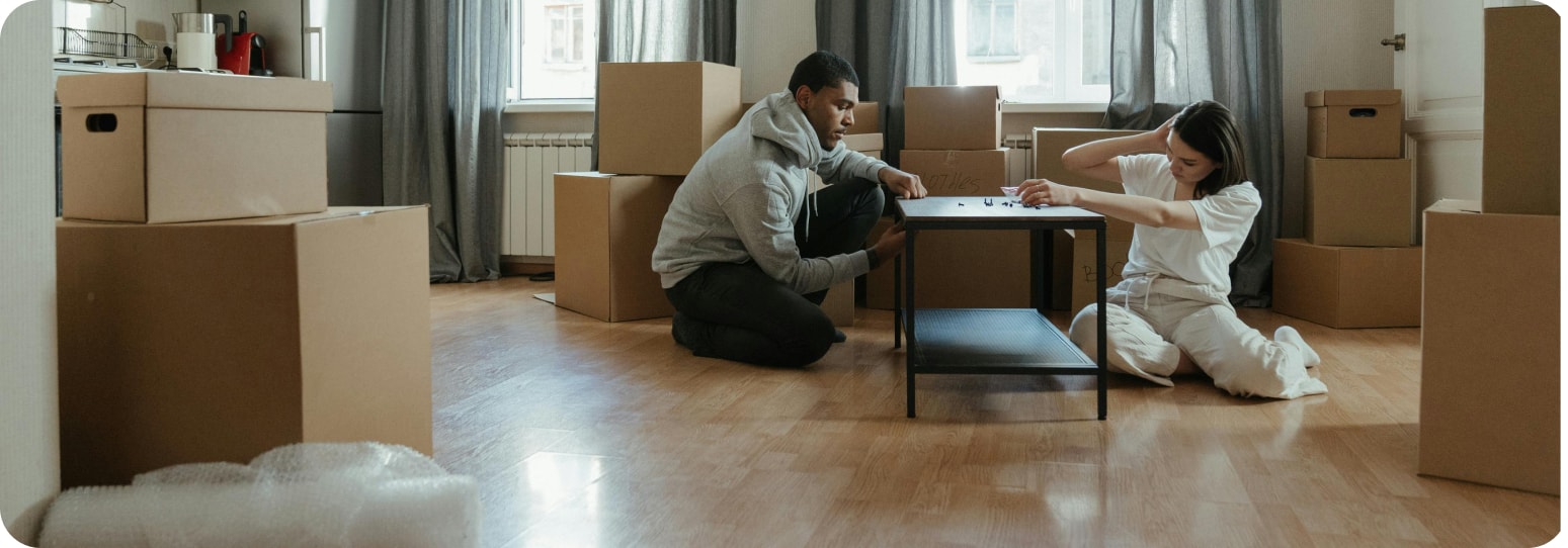 A couple putting a table together in an apartment full of moving boxes