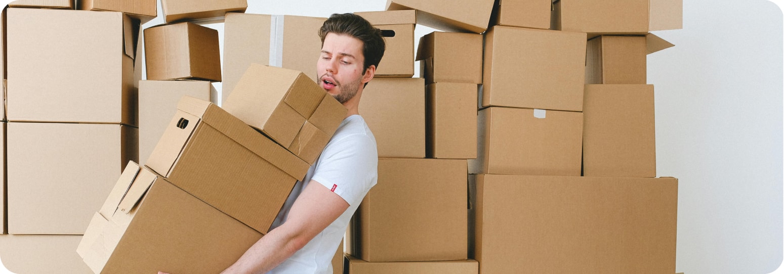 Man carrying moving boxes in front of more boxes