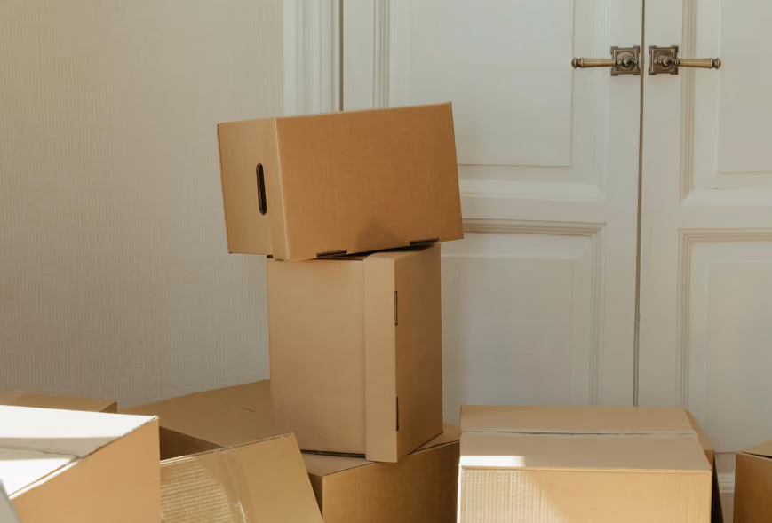 Cardboard moving boxes stacked and spread on a light floor in front of white paneled double doors