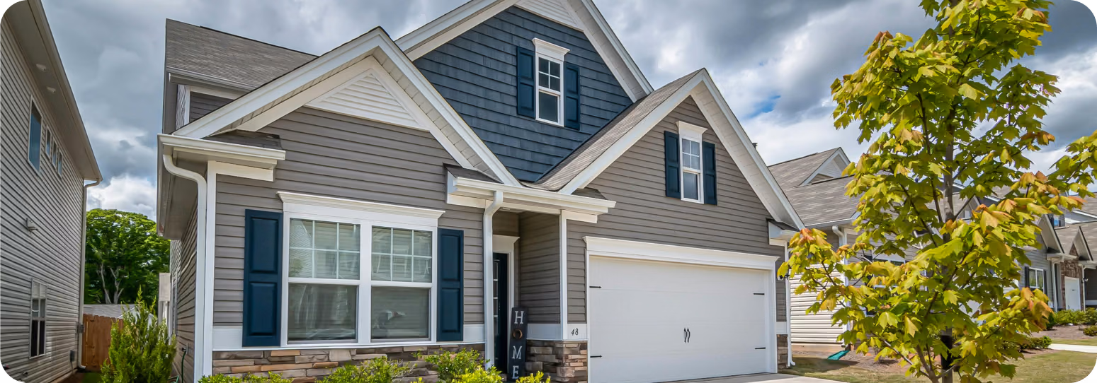 A medium sized gray home with dark blue and white accents in a neighbordhood