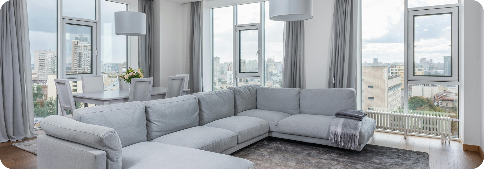 a living room with gray furniture in a high rise apartment building