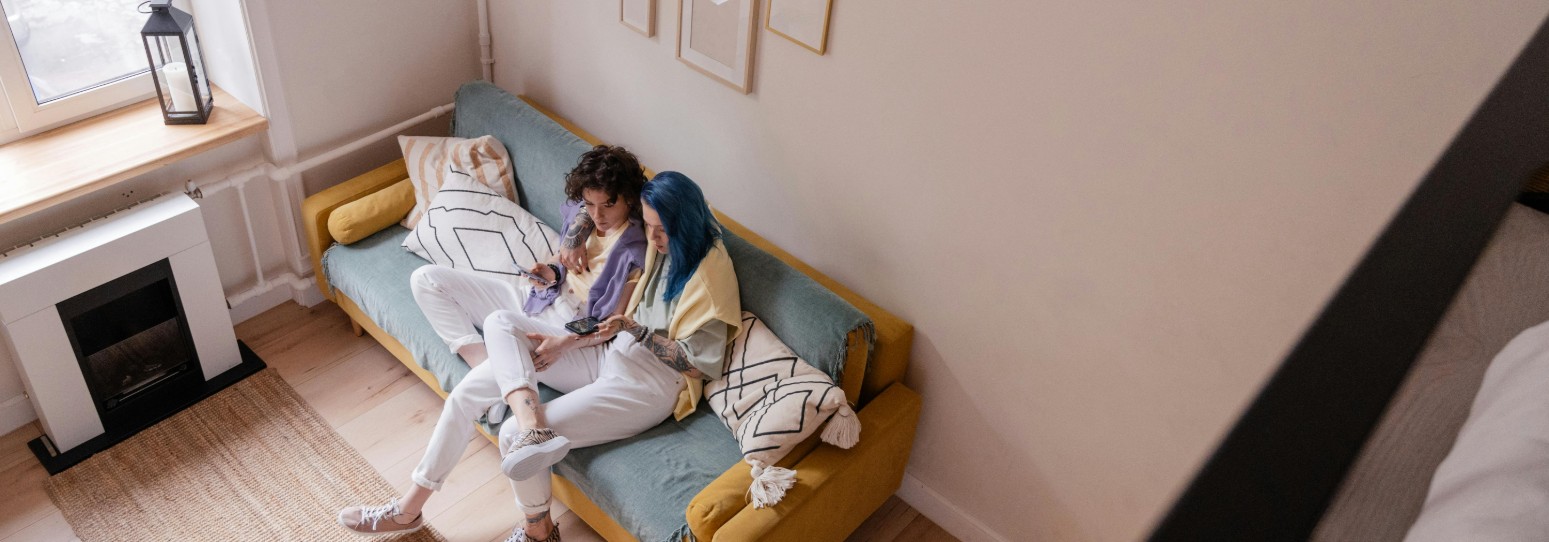 a couple sitting on a light blue and yellow couch in their living room