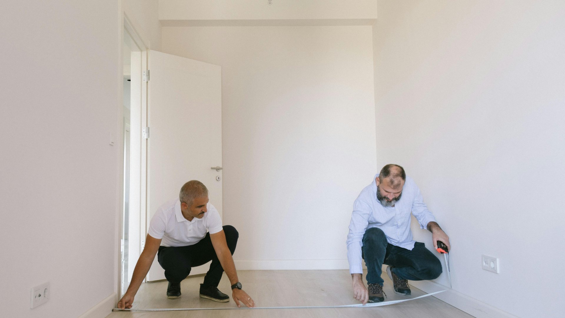 Two men measuring a room