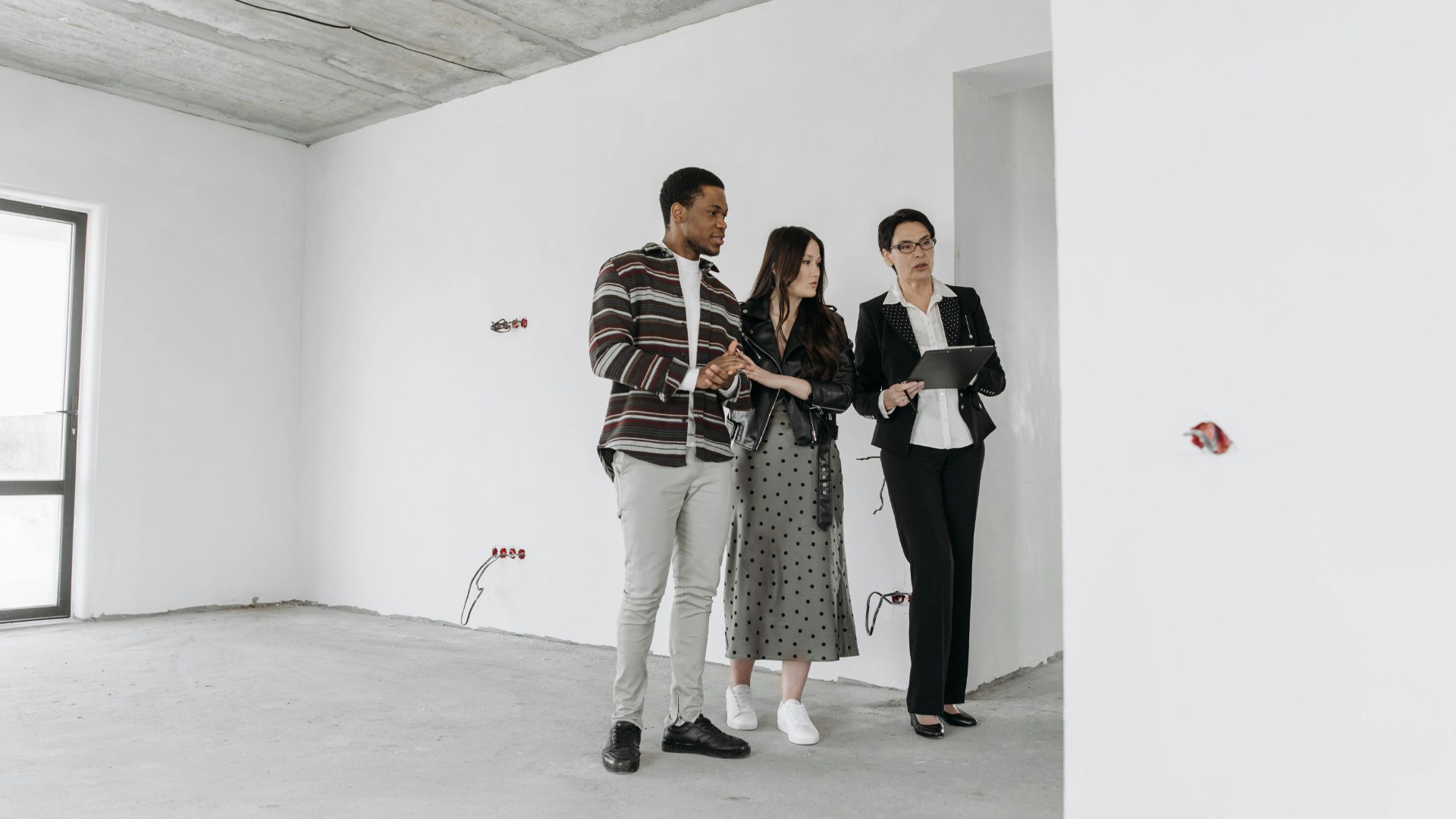 Prospective renters touring an empty apartment with a leasing agent before signing a lease.