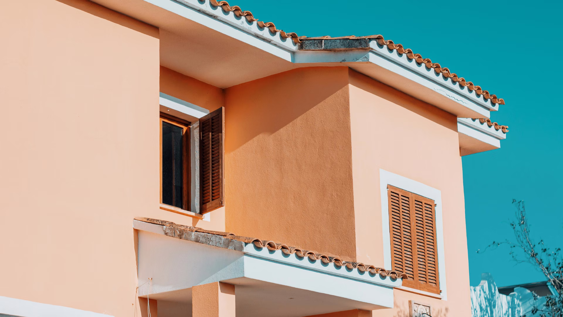 an image of a clay colored house with a white roof and a blue sky