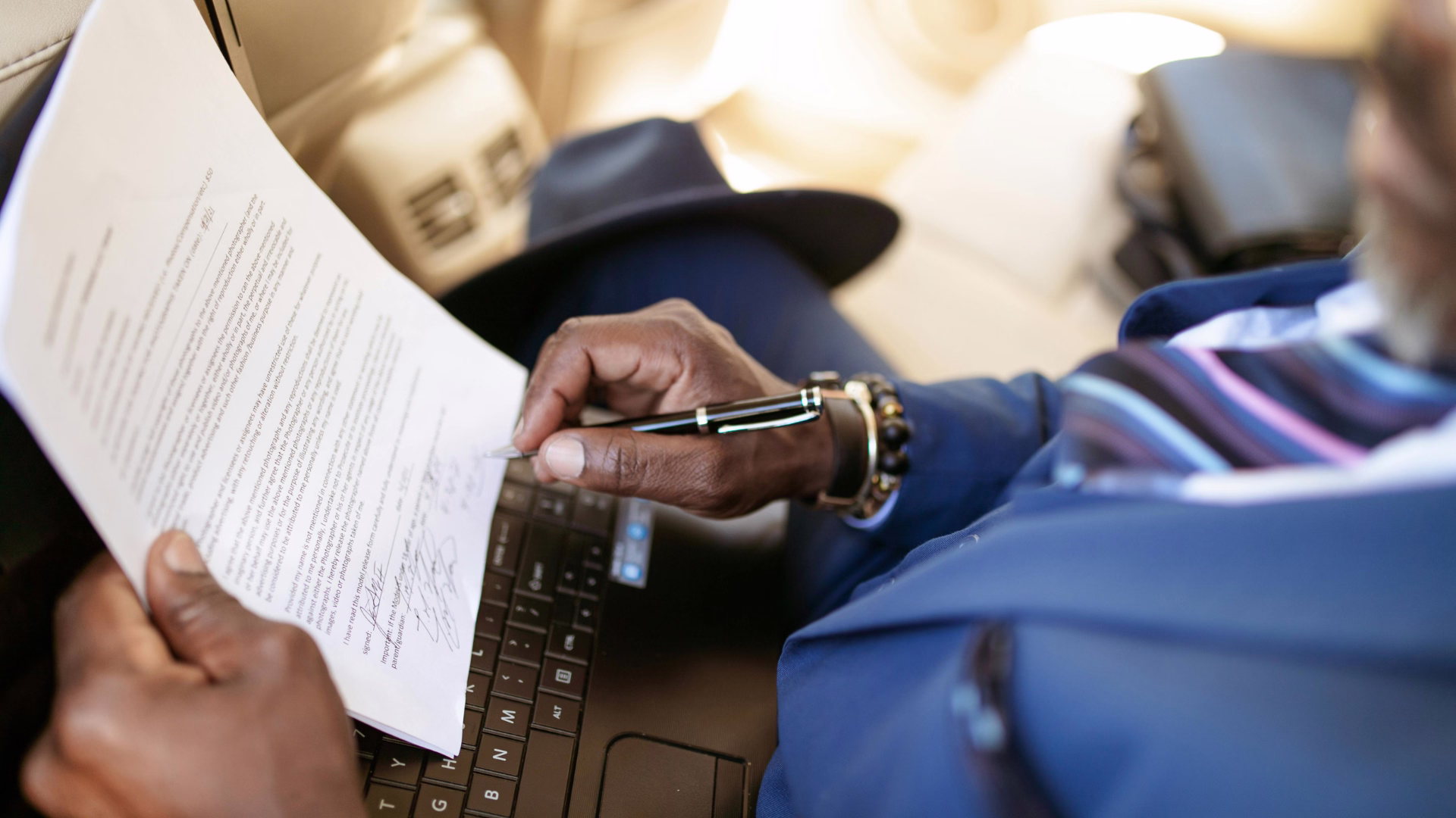 A person looking over a paper document with a pen sitting down