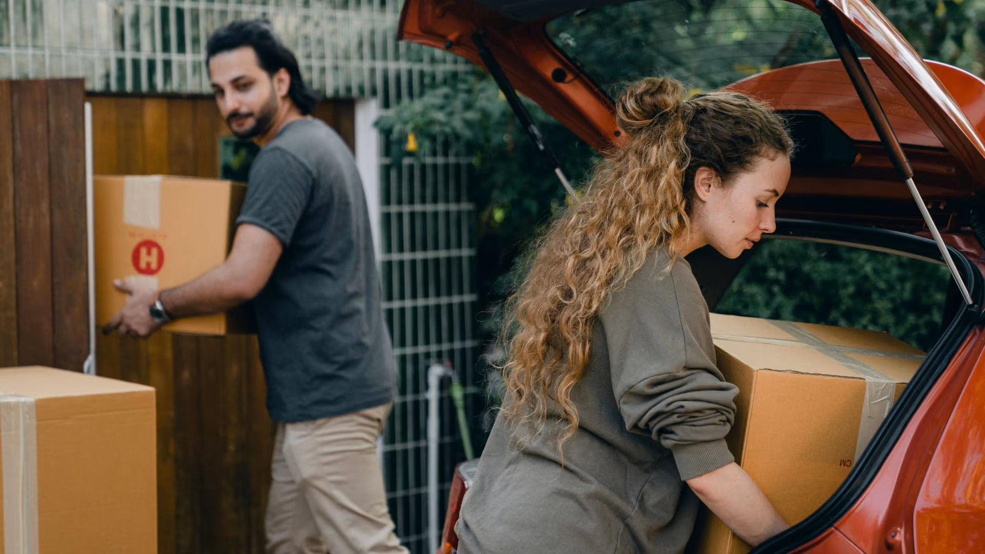 New residents unloading moving boxes from a car during move-in day at an apartment community.