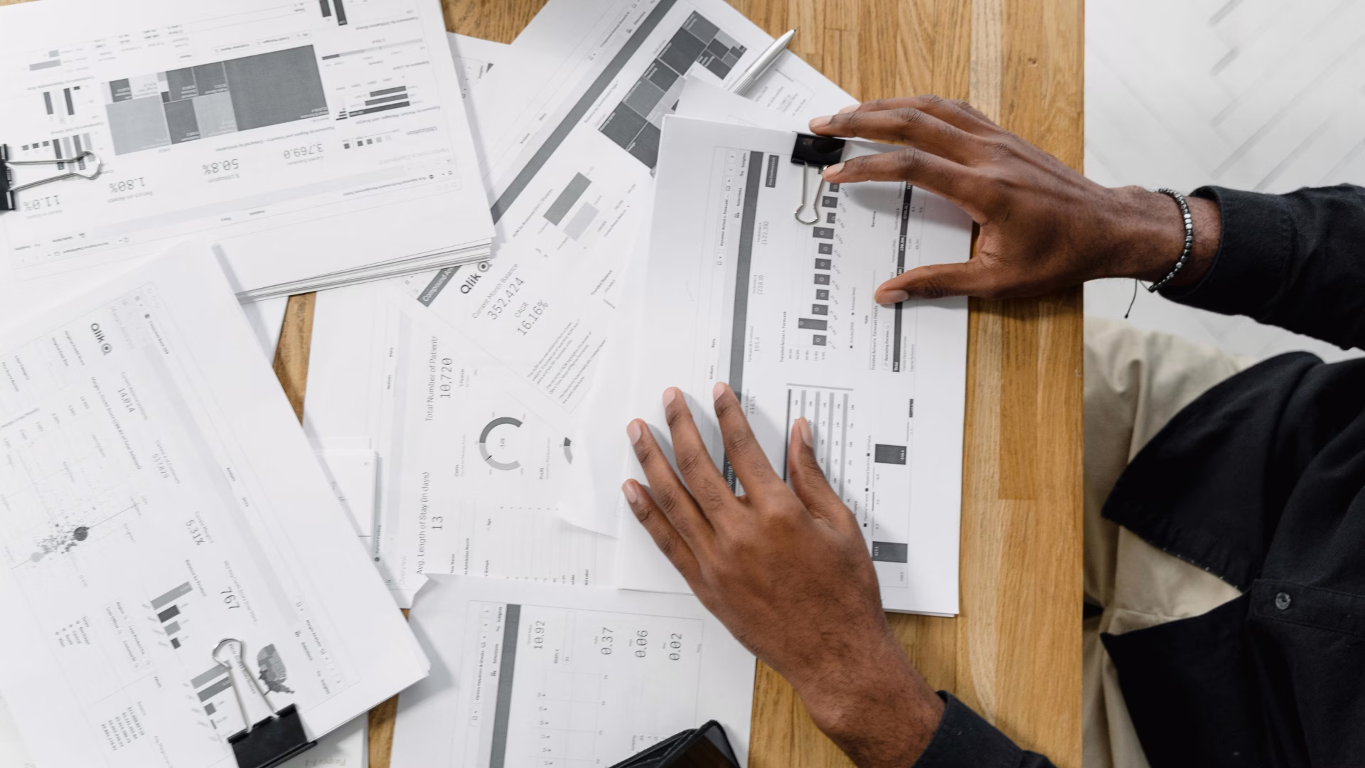 A person sitting at a desk with a bunch of various papers with data, charts and statements.
