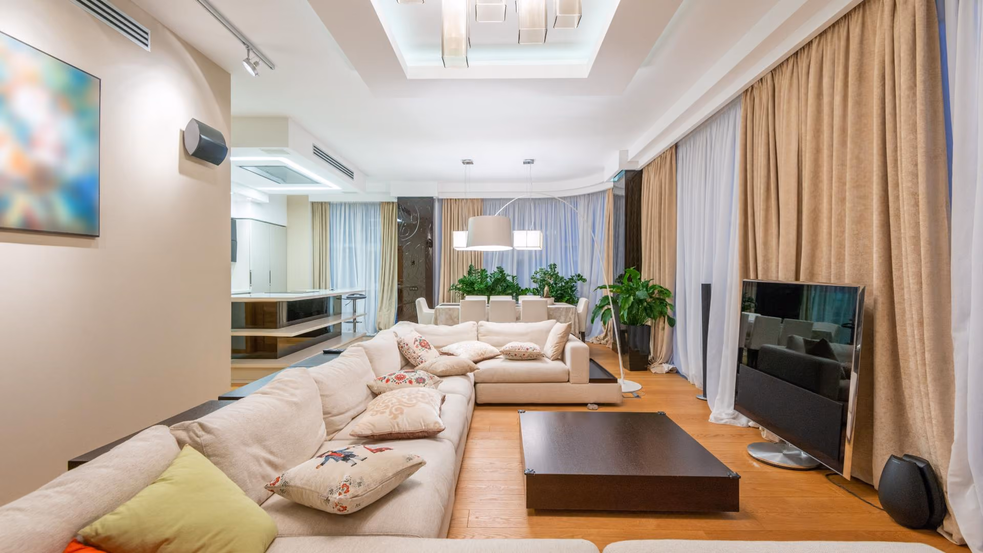 Modern apartment living room with sectional sofa, layered lighting, large windows, and renter-friendly décor.