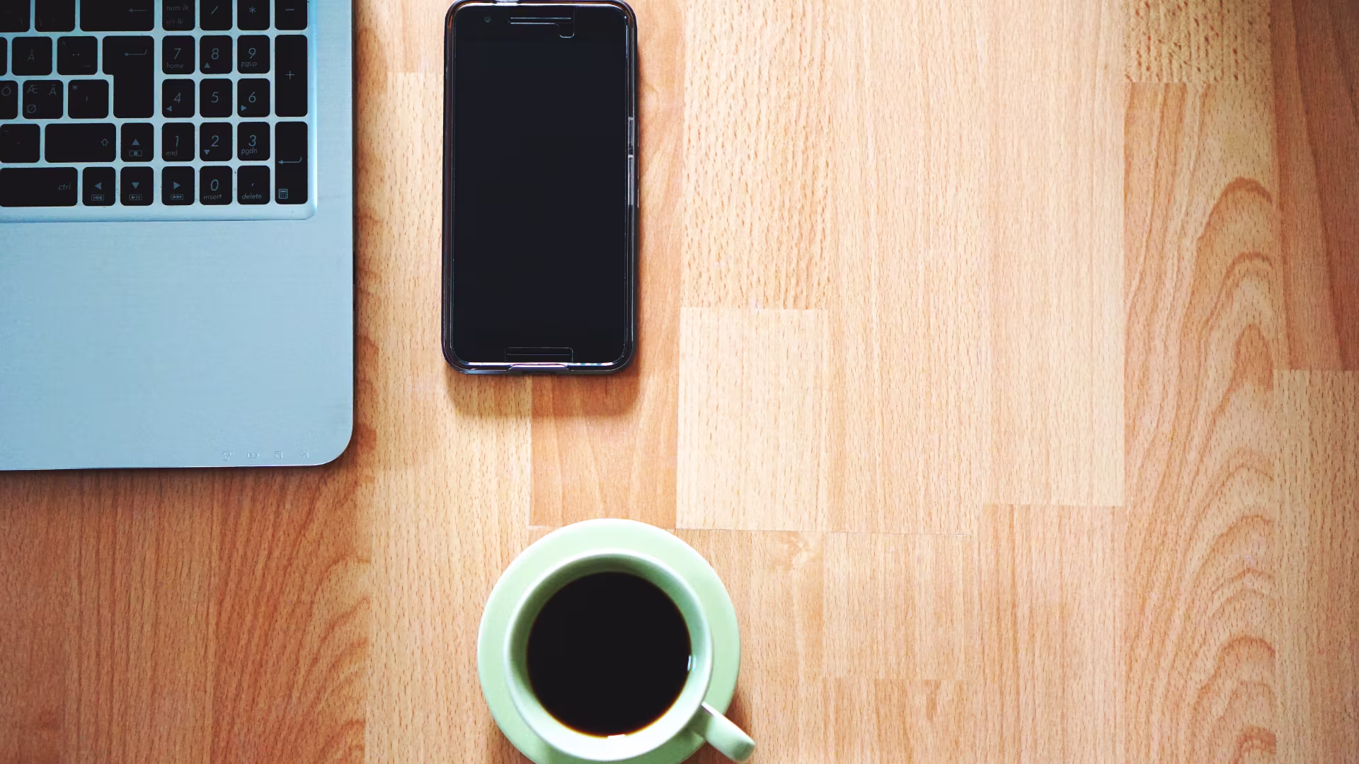 overhead image of a smartphone, laptop and a cup of coffee