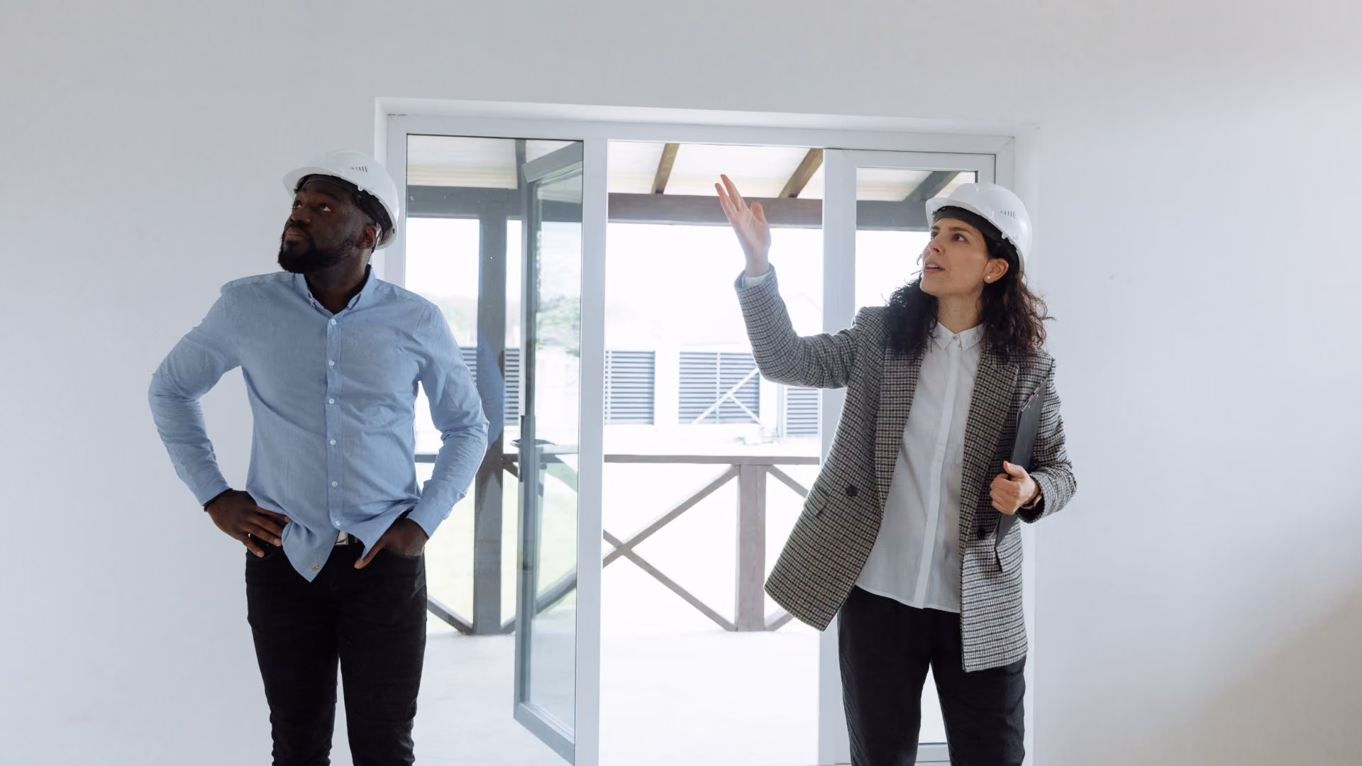 Homebuyer and inspector wearing hard hats during a residential home inspection.