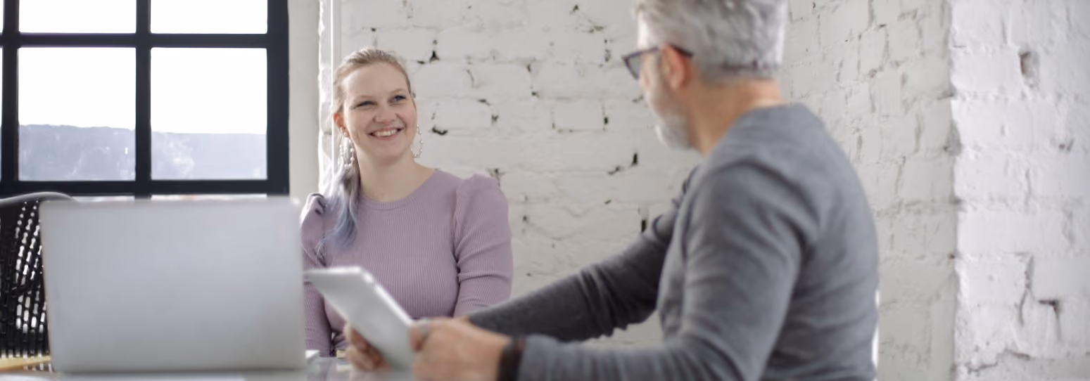 A leasing agent and a potential client in an office smiling