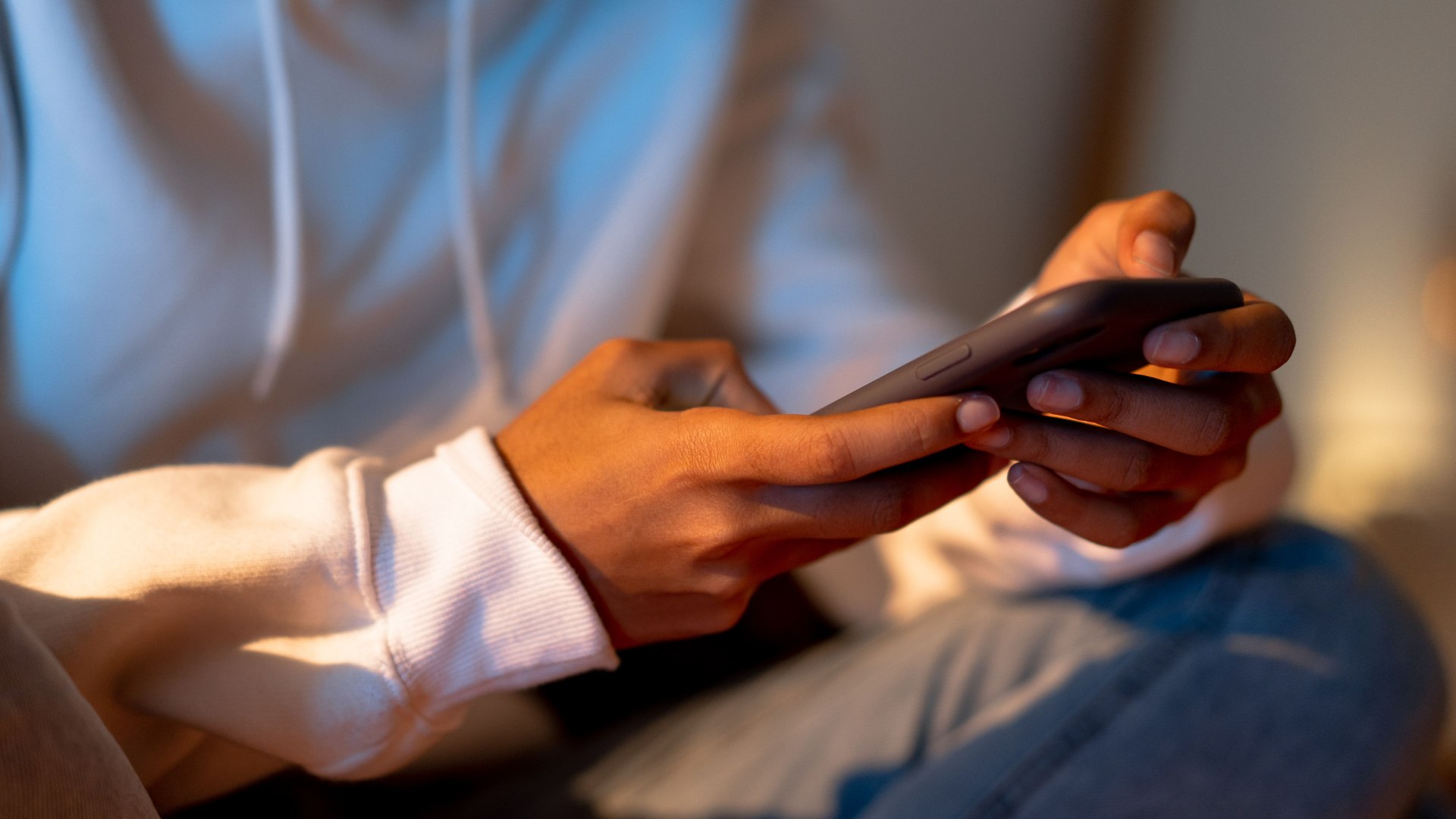 Image 1 (phone):  Close-up of a person scrolling on a smartphone in a dimly lit room