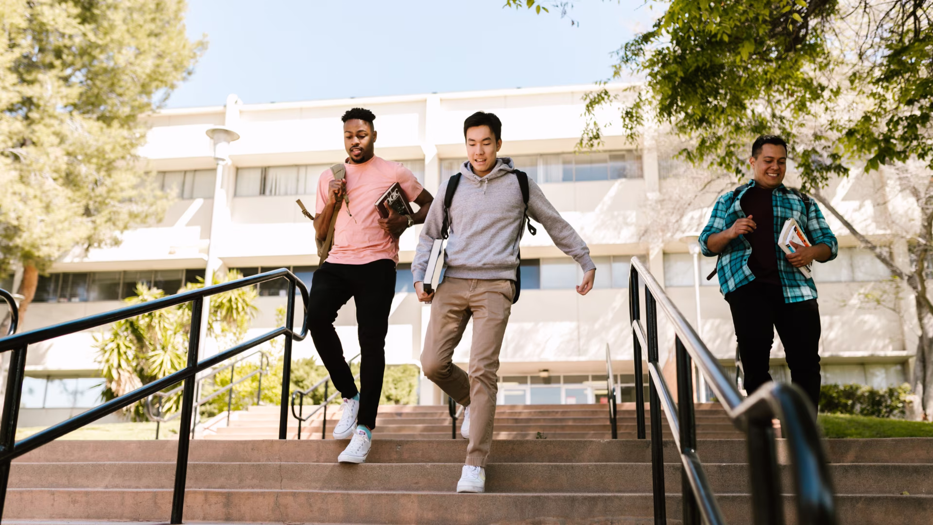 3 college students going down a set of stairs on campus