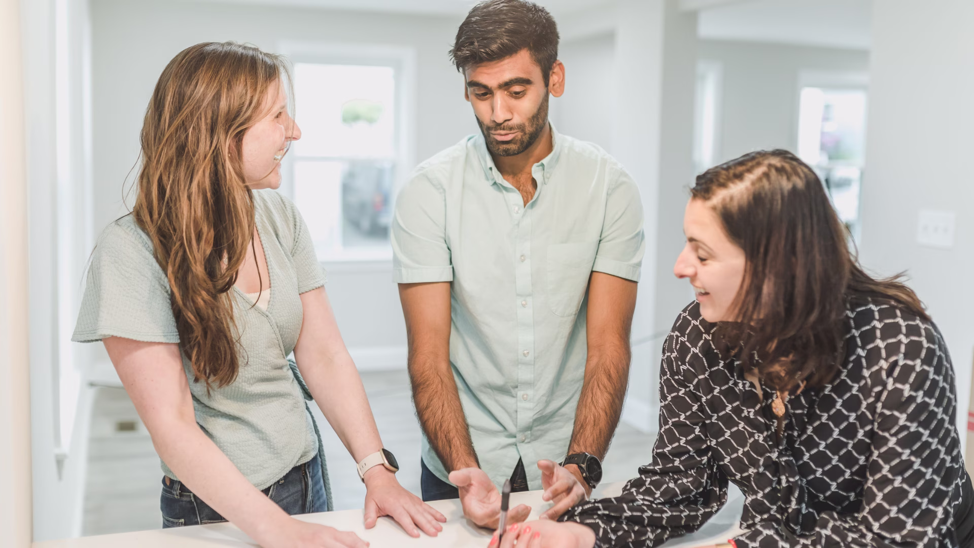 three people talking at a kitchen table standing up