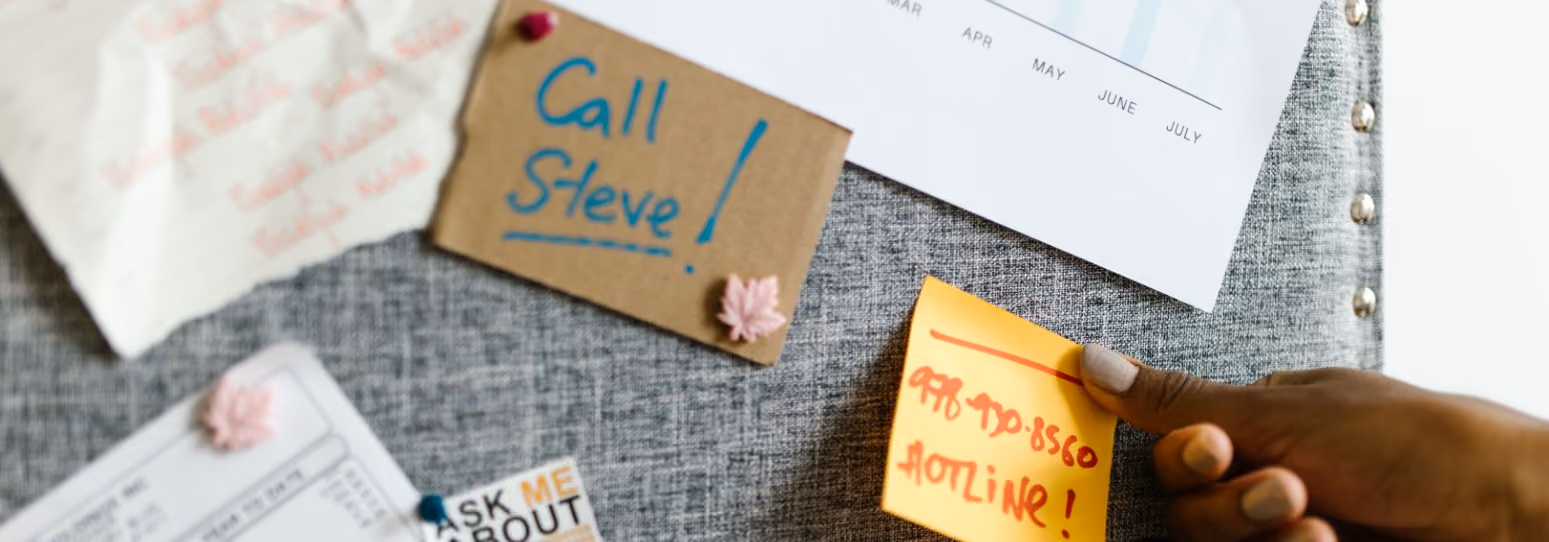 a person putting a sticky not reminder on a reminder board