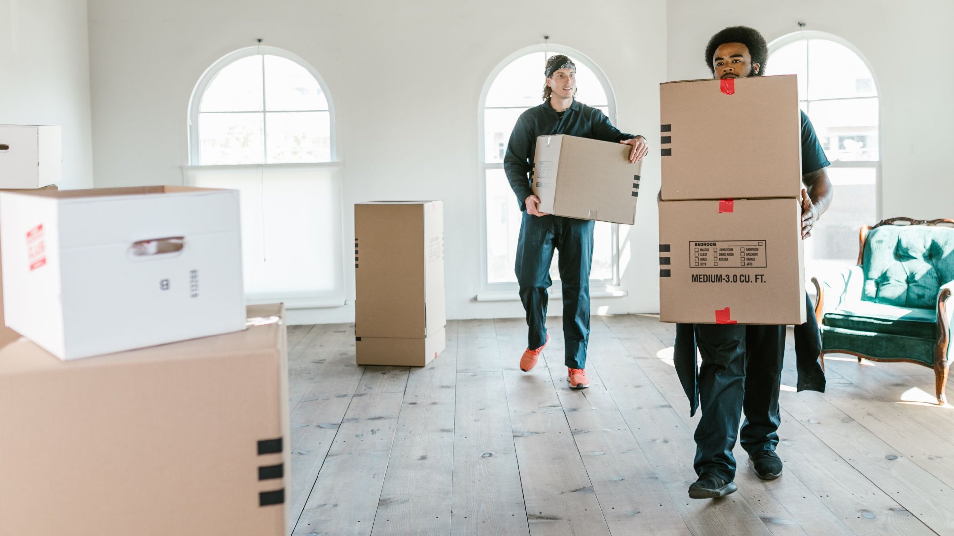 Two people carrying moving boxes into a new apartment.