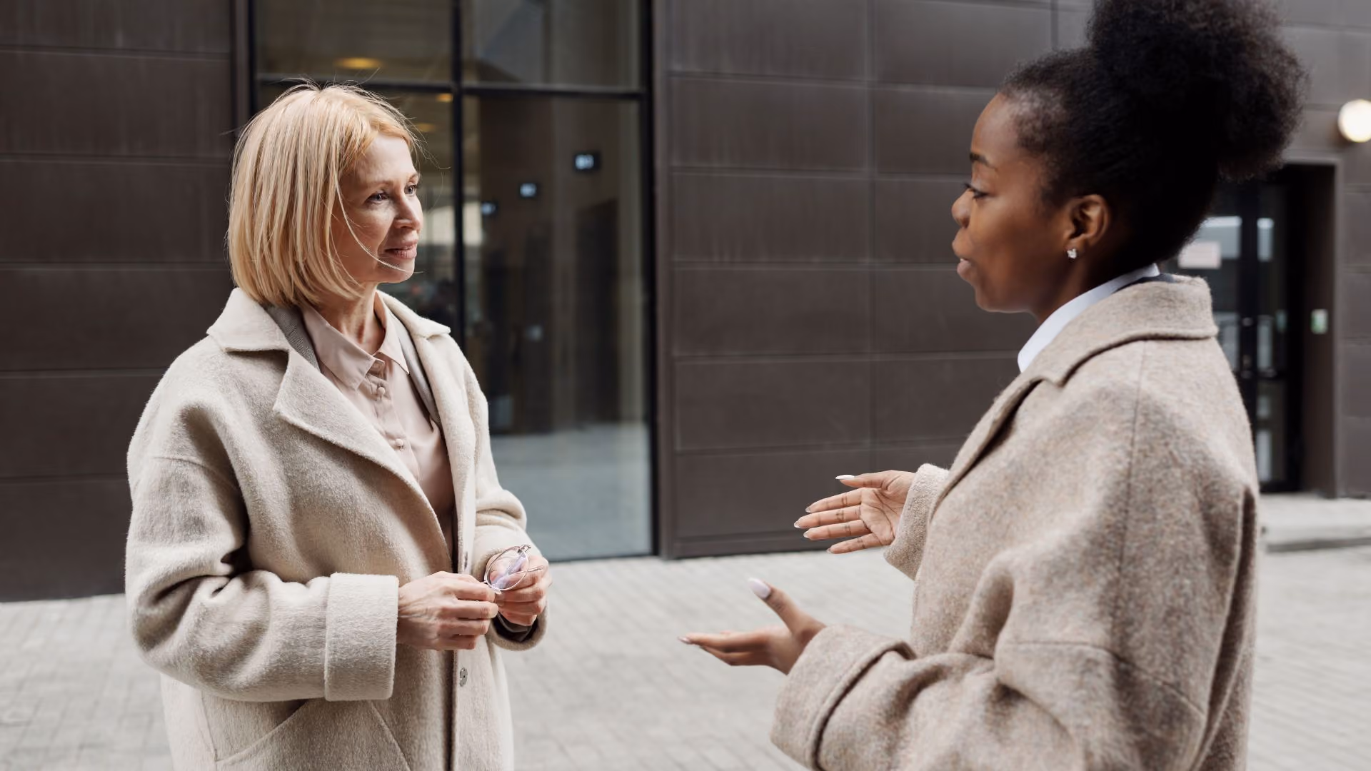 Two people talking outside an apartment building.