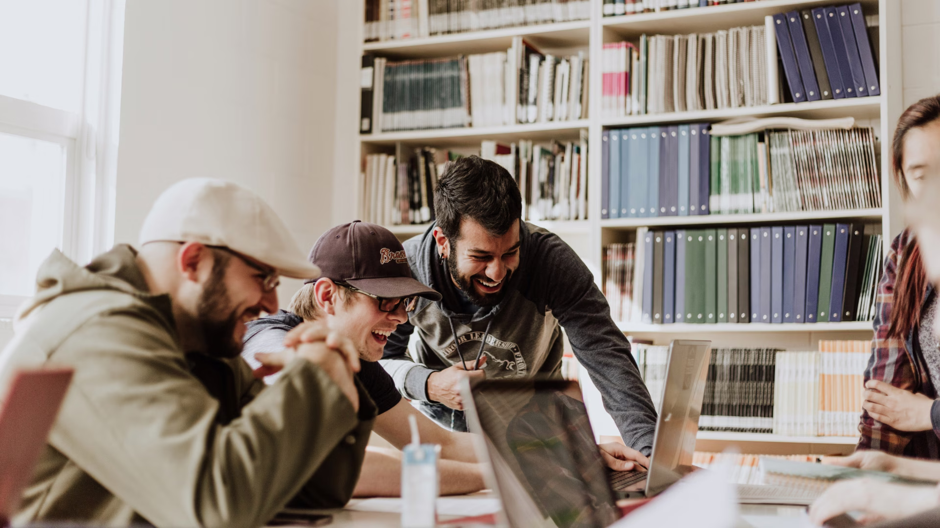 a group of college students sitting at a table looking at a laptop