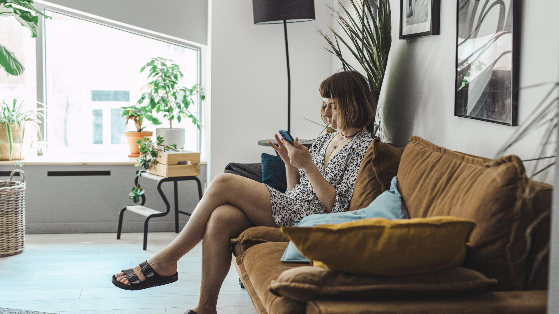 A person sitting on a yellow couch a living room on their phone