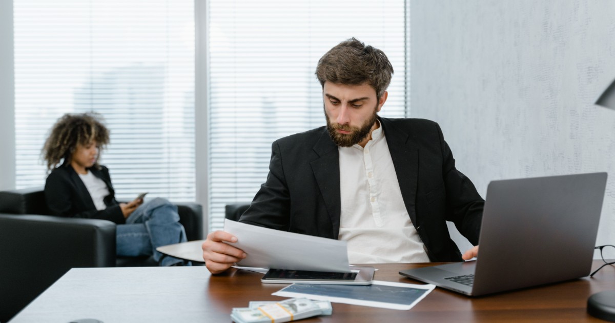 2 people looking over papers and documents in a conference room or office
