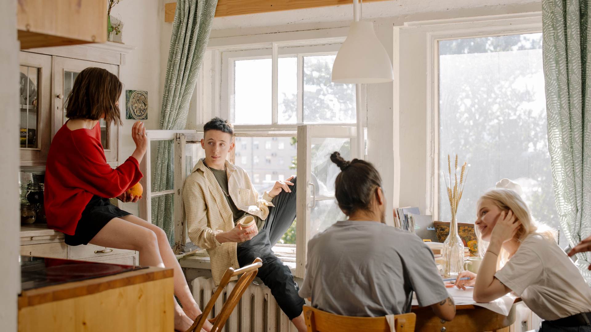 Group of roommates talking together around a table in a shared apartment.