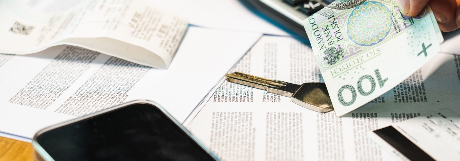 paper documents, cash, keys, and a phone laid out on a table