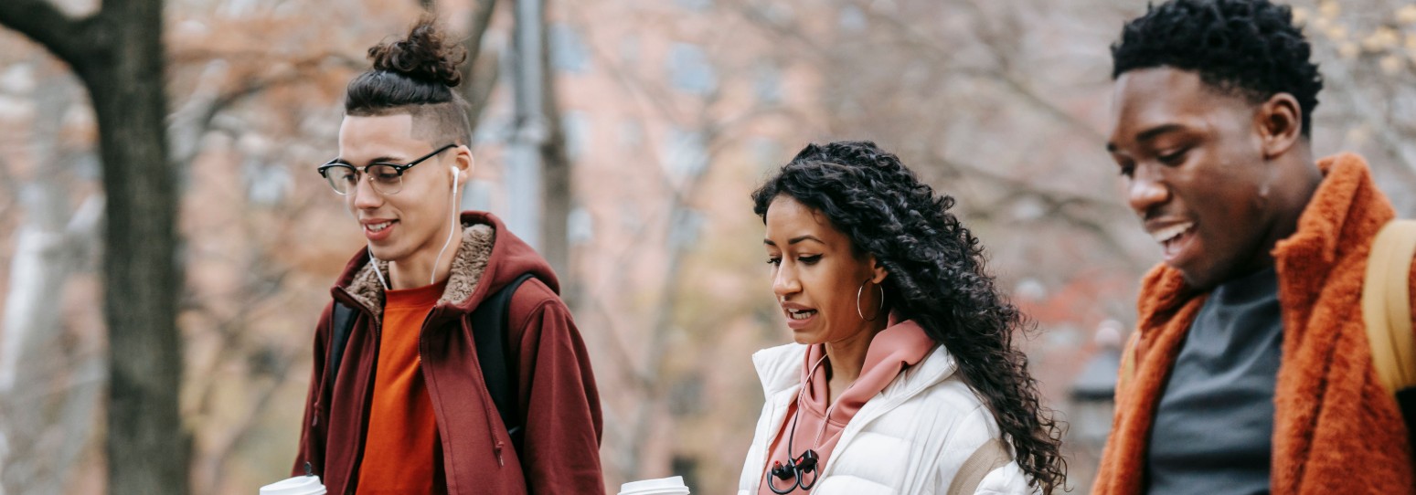 3 young adults walking and talking to each other