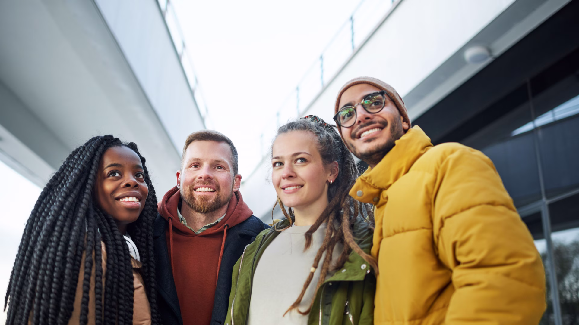 4 young adults in warm clothes outside talking to each other