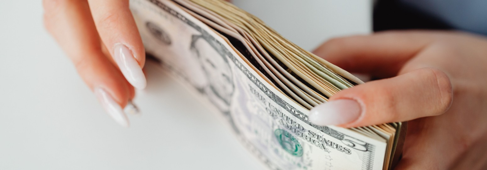 a person holding a wad of cash on a table
