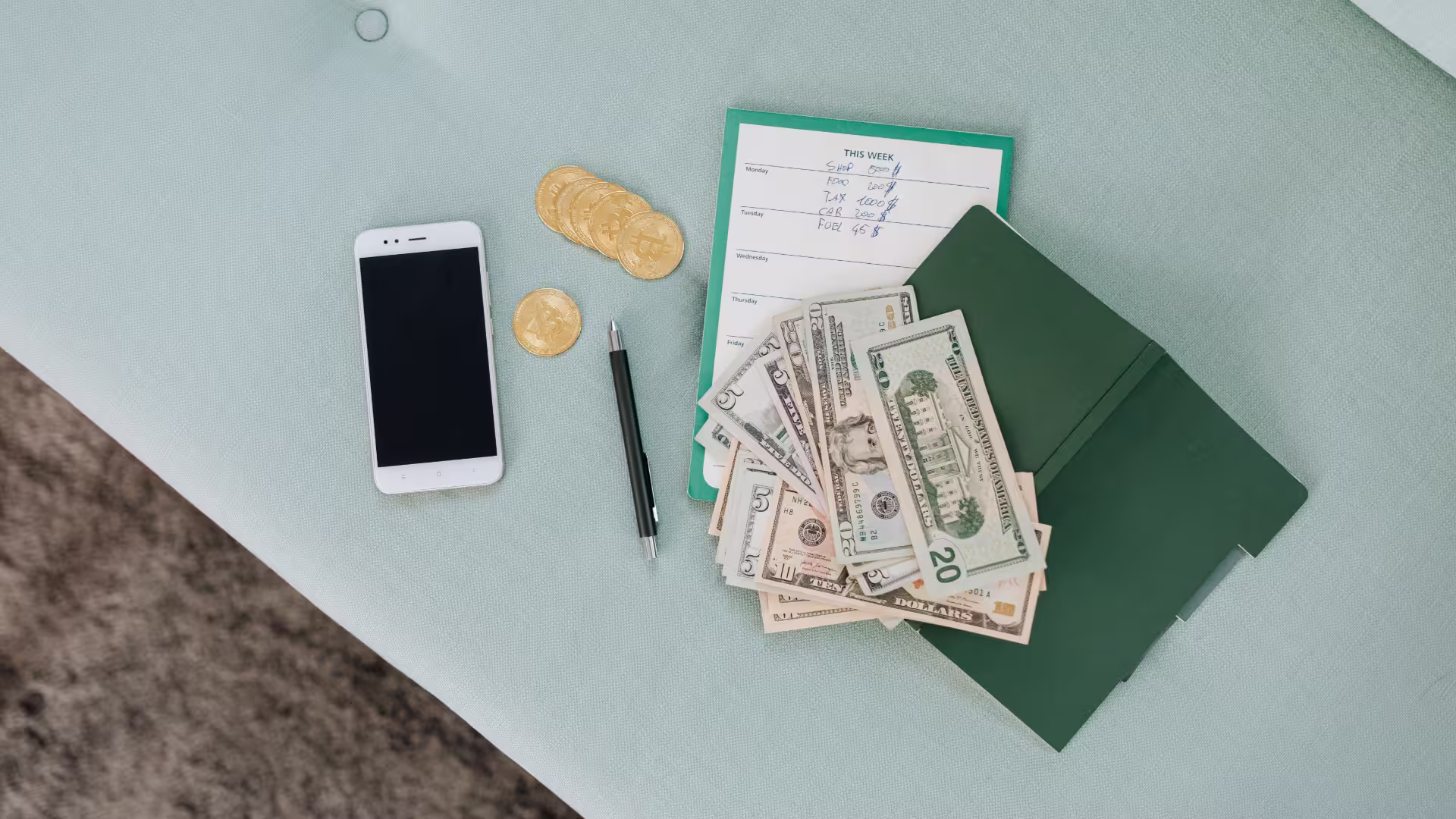 a overhead view of a table with a smartphone cash, coins, and documents