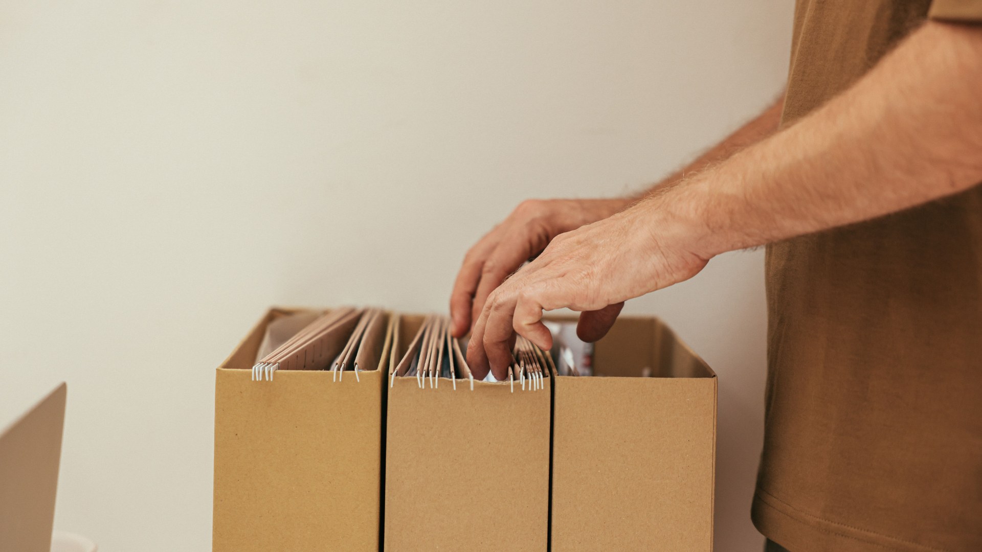 Person organizing files in cardboard storage boxes.