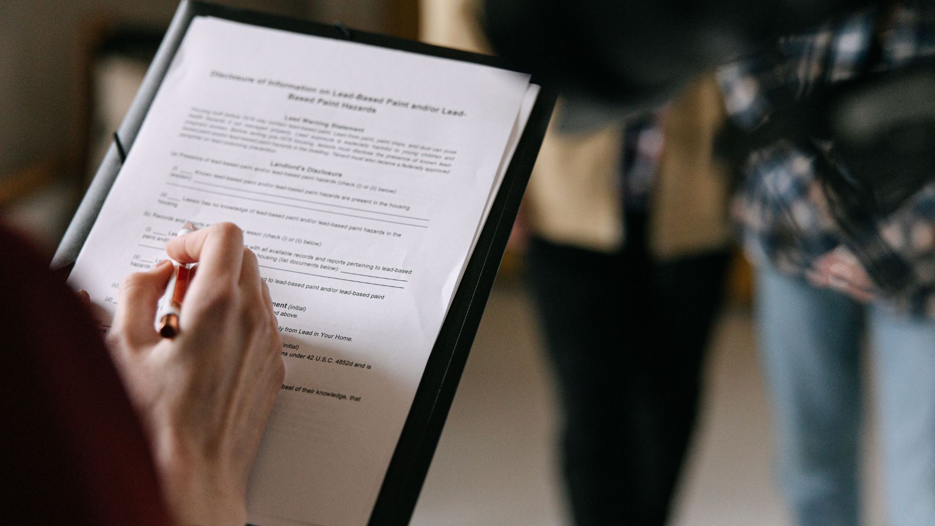 Person filling out a form on a clipboard.