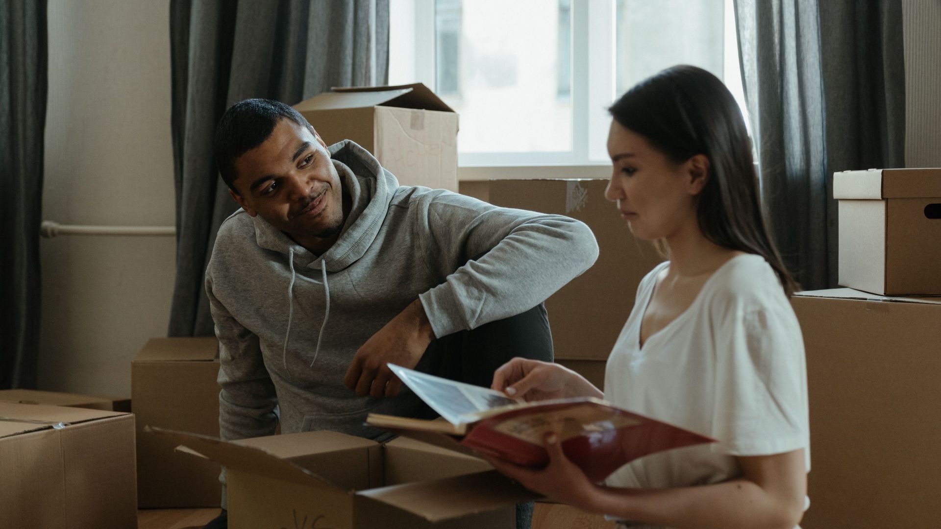 Two people looking through documents while surrounded by moving boxes.