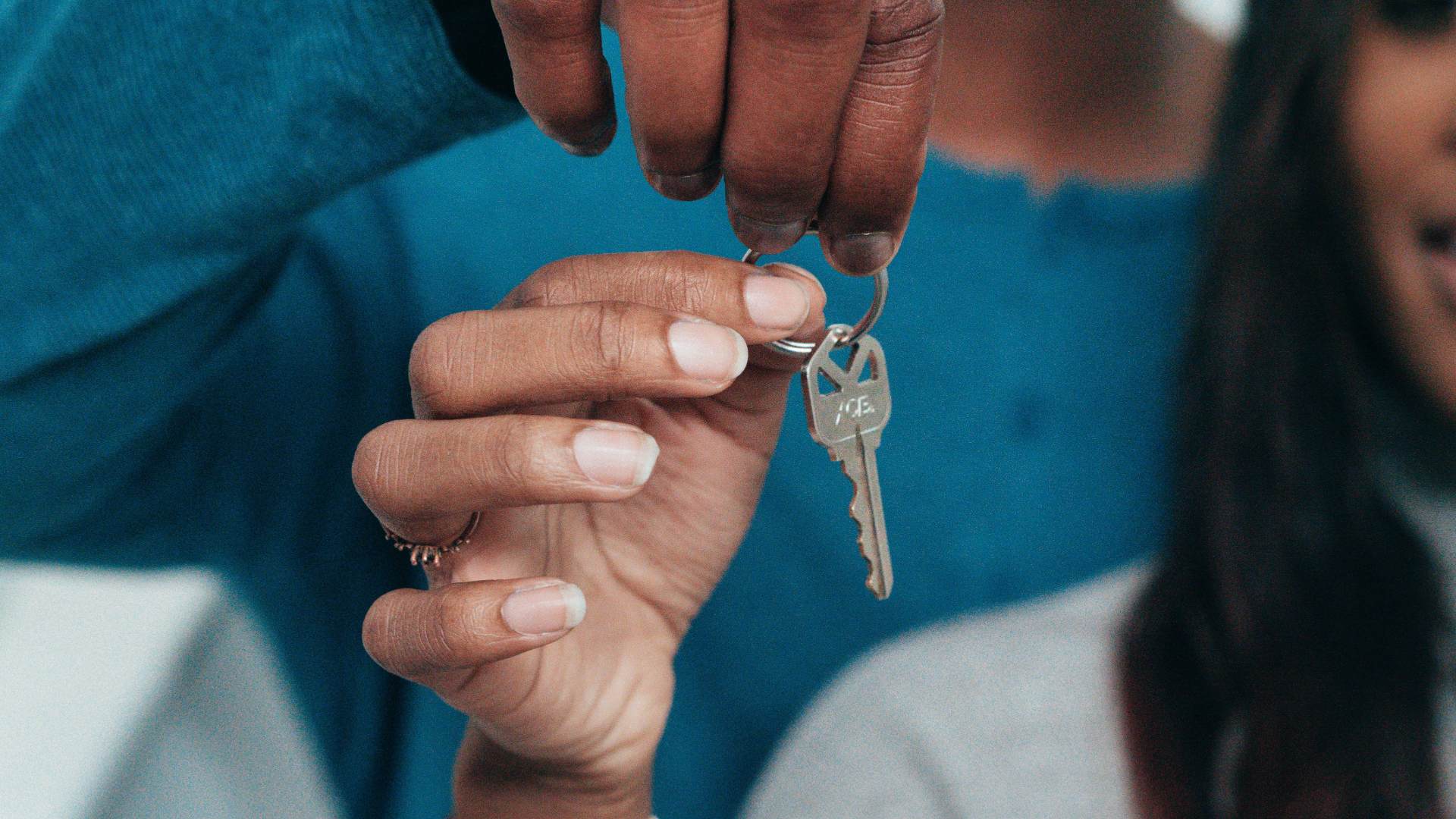 Close-up of a person handing over house keys to a new resident.