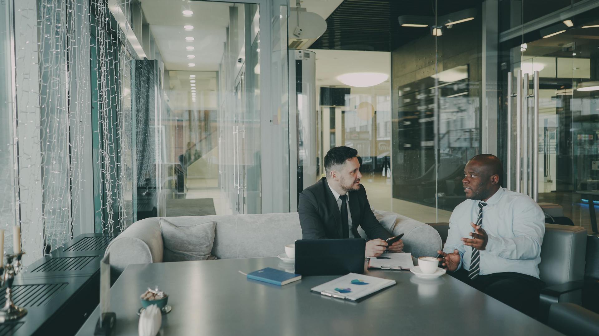 A property manager sitting at a desk having a professional discussion with a tenant about lease termination terms.