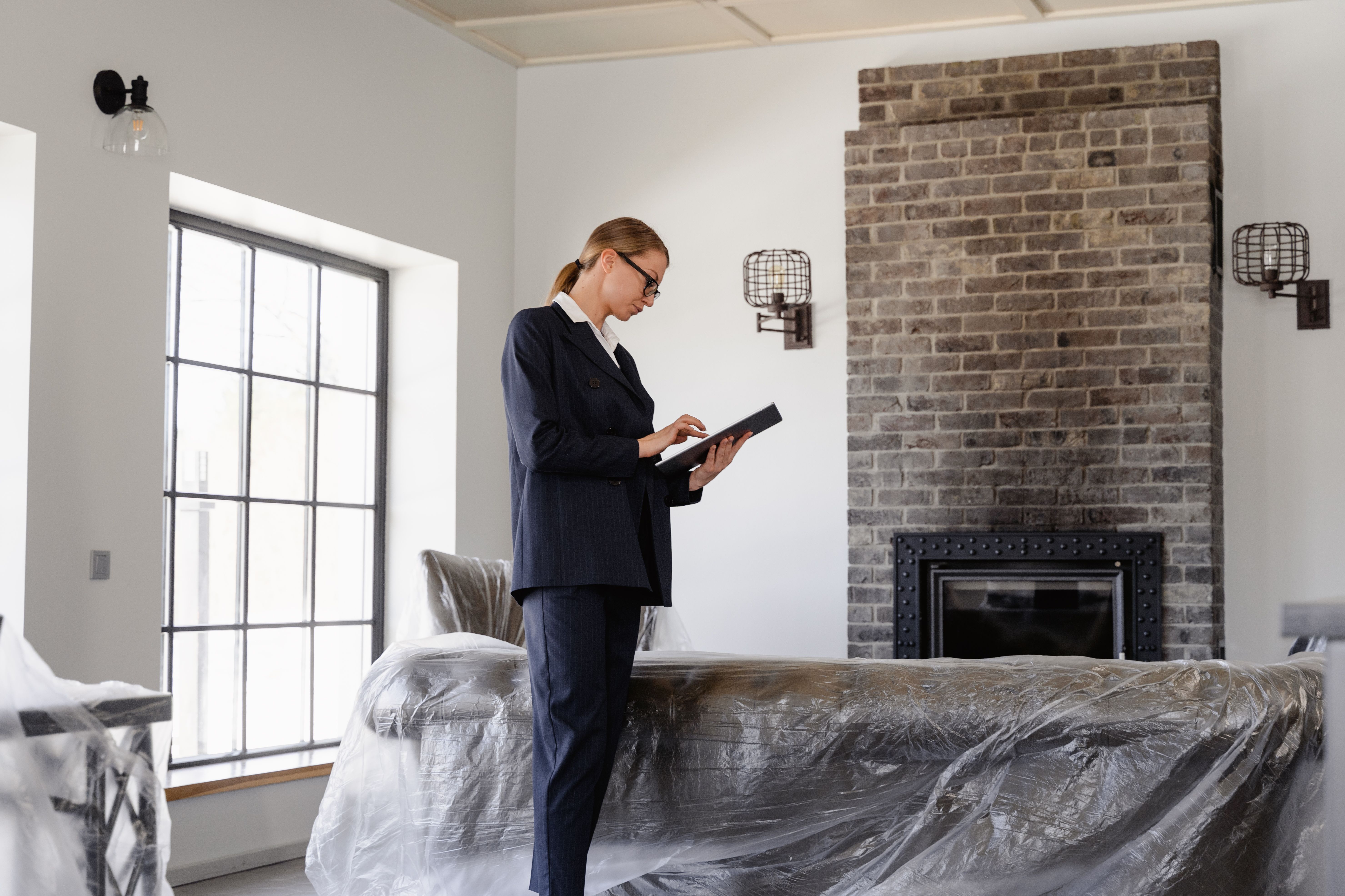 Property manager in a suit standing in an apartment living room while using a digital tablet.