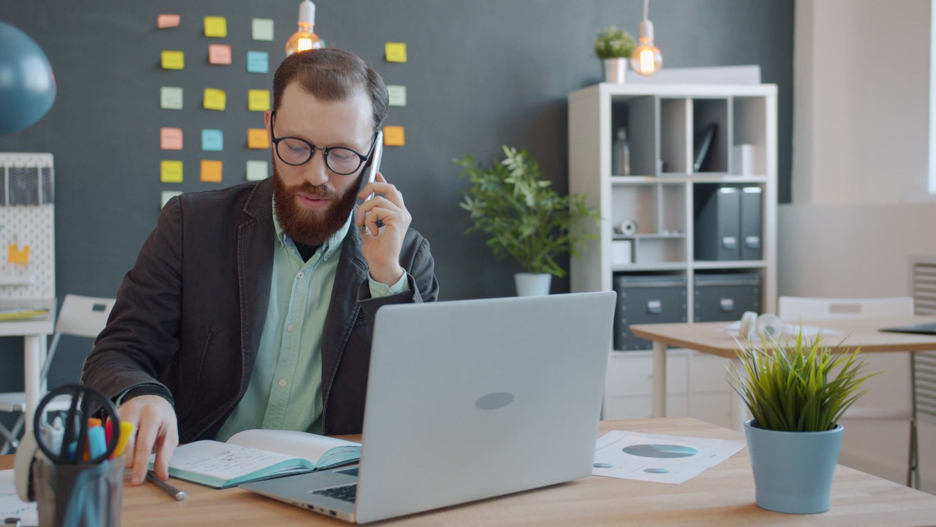 property manager on their phone sitting at a table with a laptop and documents