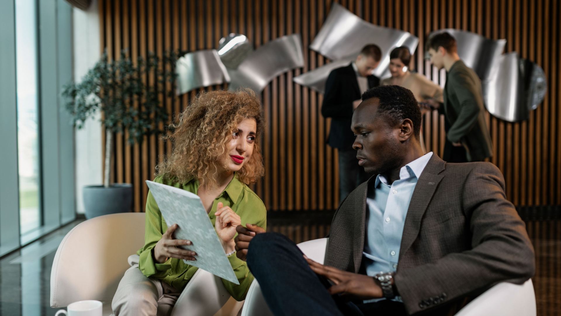 Two professionals discuss a document in a modern office.