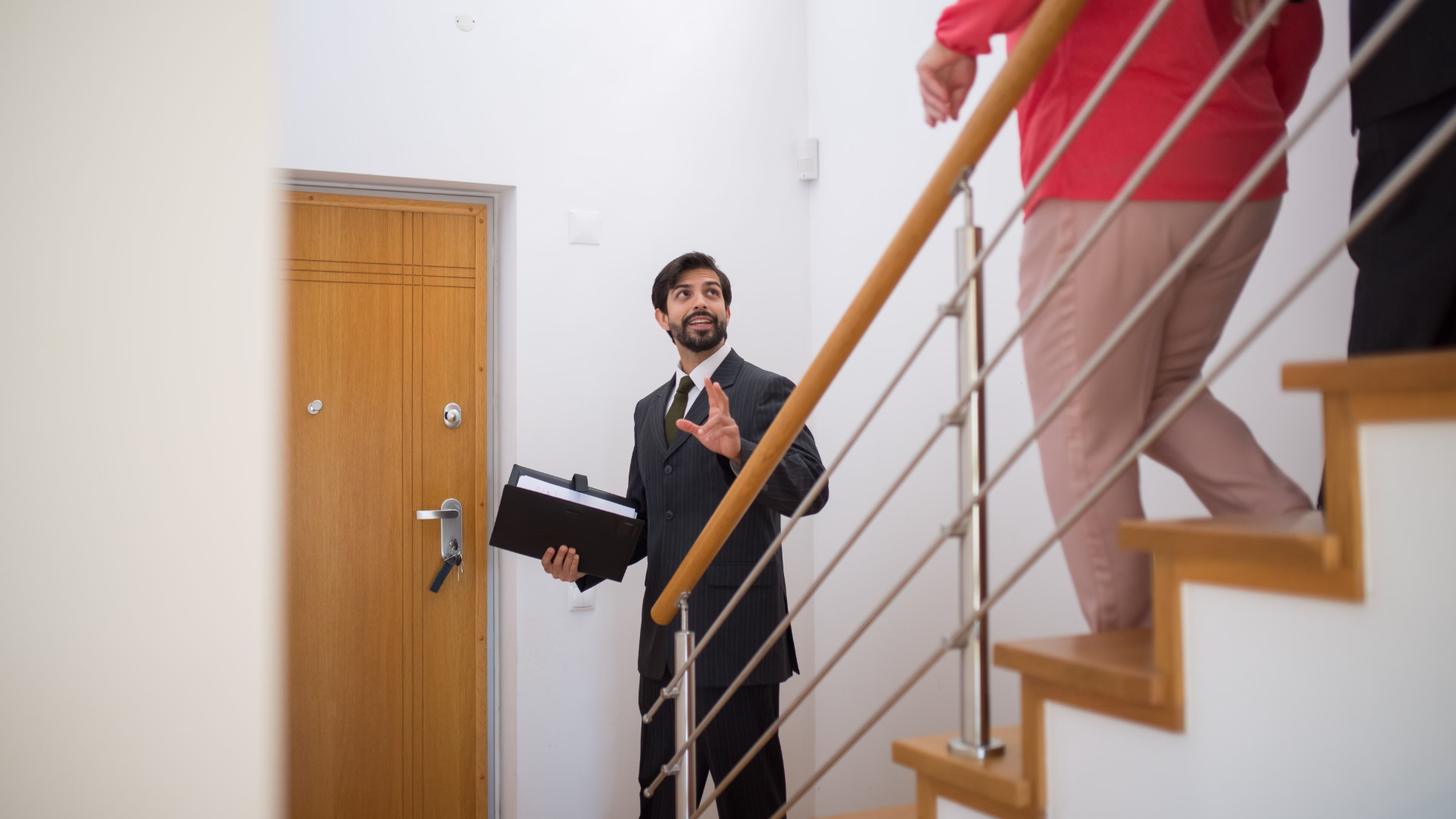 leasing agent giving apartment tour to couple walking down stairs