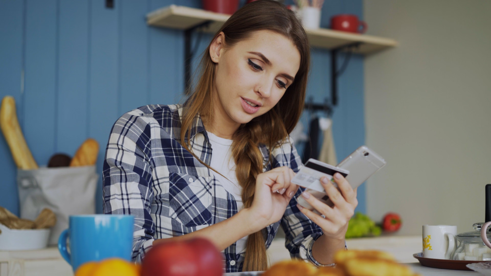 young renter paying bills on smartphone at kitchen table