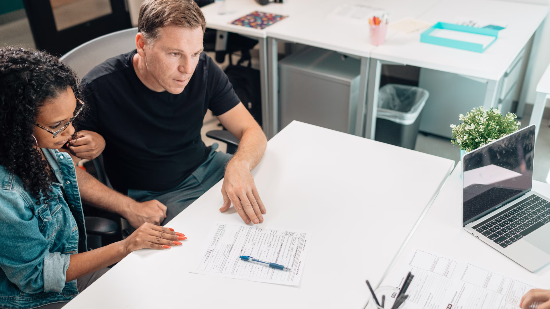 leasing consultant reviewing paperwork at desk laptop with tenants
