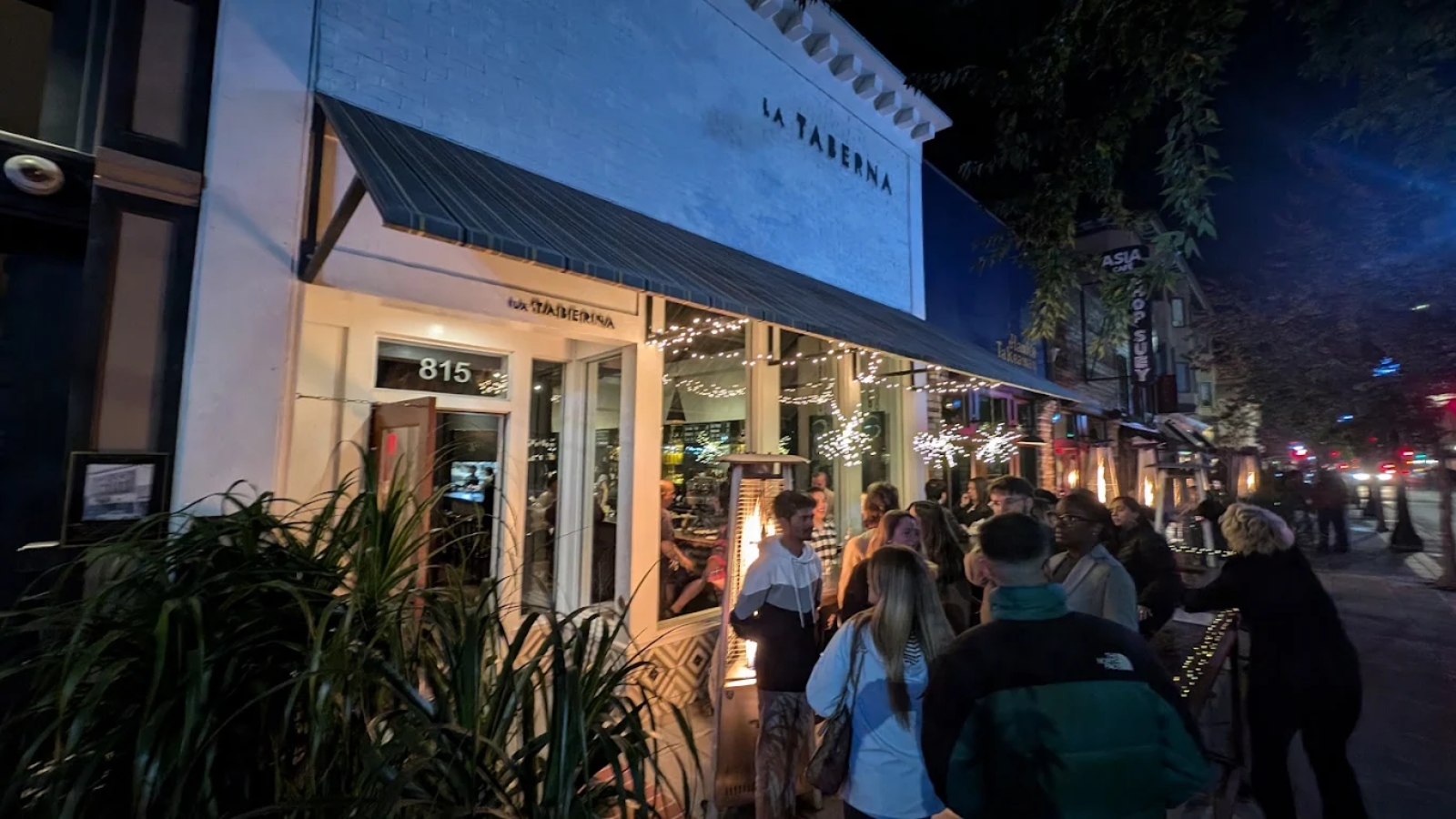 Guests gather outside La Taberna in downtown at night with string lights and a lively atmosphere.