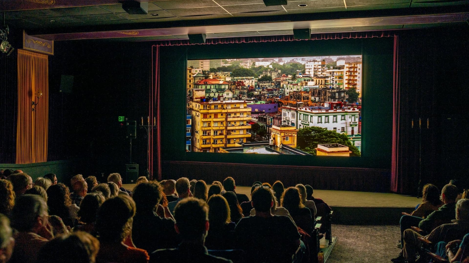 Interior view of Cameo Cinema showing audience members seated in rows watching a colorful film projected on the main screen in the classic movie theater setting.
