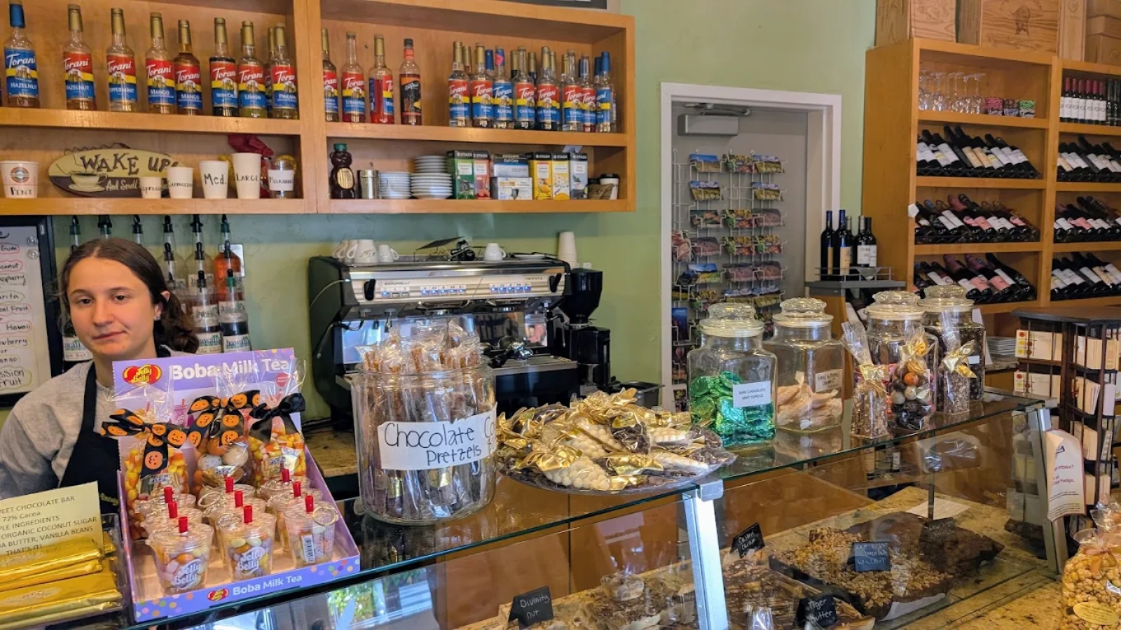 Vintage Sweet Shoppe features a charming candy shop interior with glass display cases filled with chocolate treats, shelves of colorful beverages, and a smiling employee holding candy products.