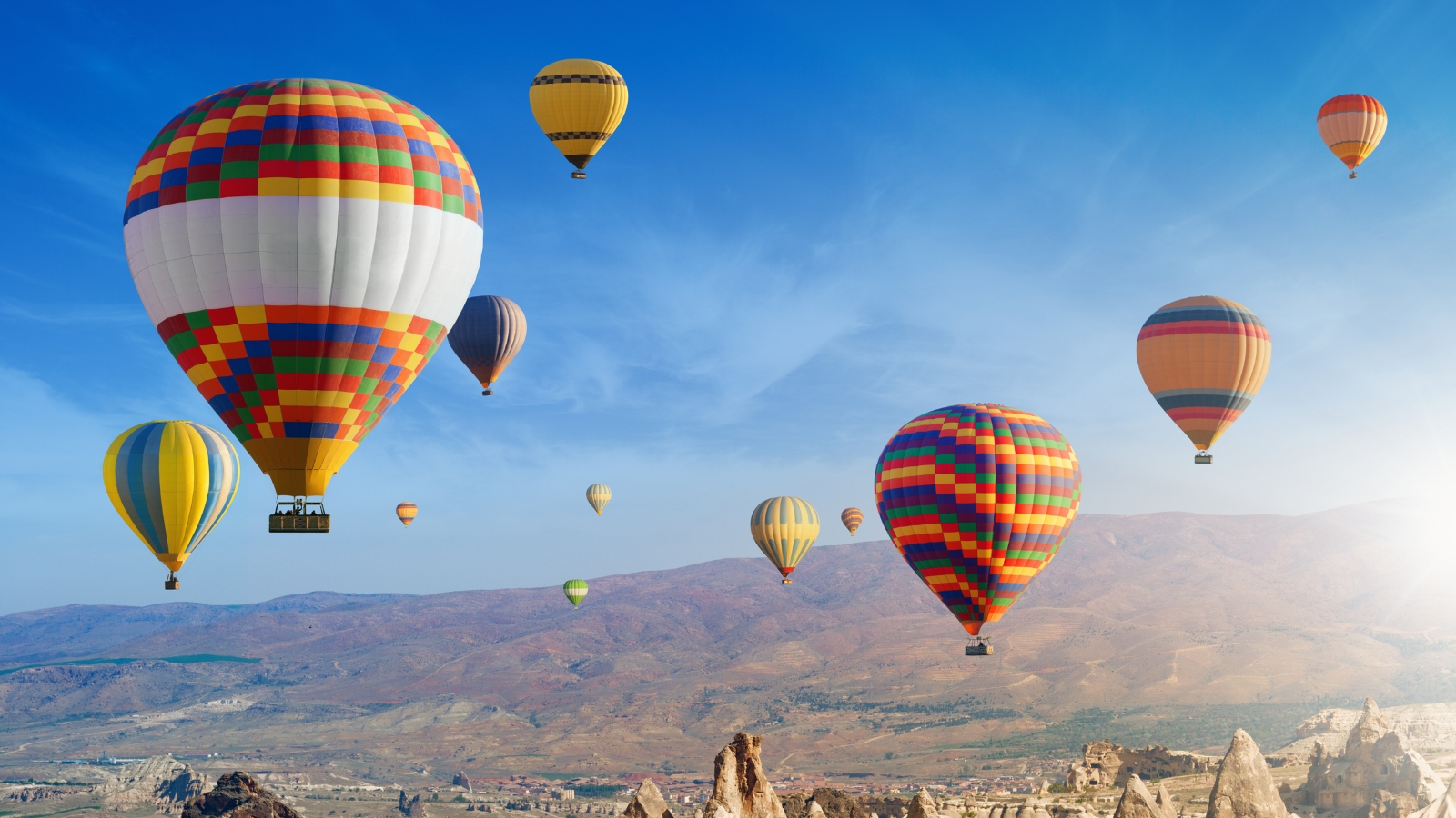 Colorful Napa Valley balloons floating over scenic vineyard landscape with mountains and valleys during hot air balloon ride experience