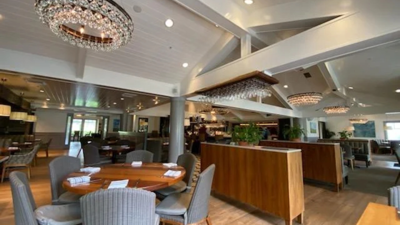 Brix Restaurant And Gardens - contemporary fine dining restaurant with open floor plan, round wood table with upholstered chairs, crystal chandeliers, wooden bar counter, high ceilings, skylights, and modern elegant design creating an airy sophisticated atmosphere