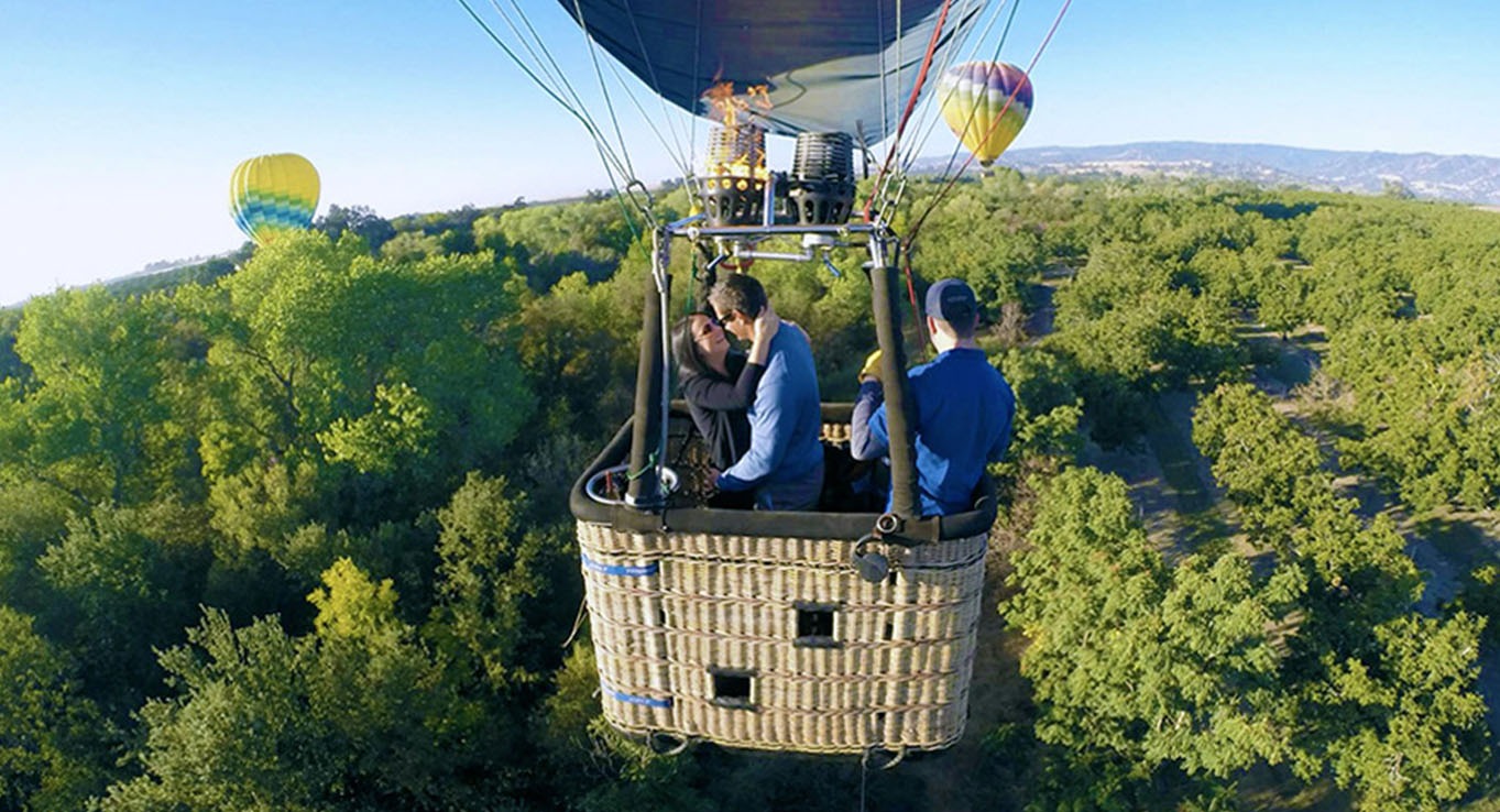 Couple embracing in a hot air balloon above Napa Valley at sunrise