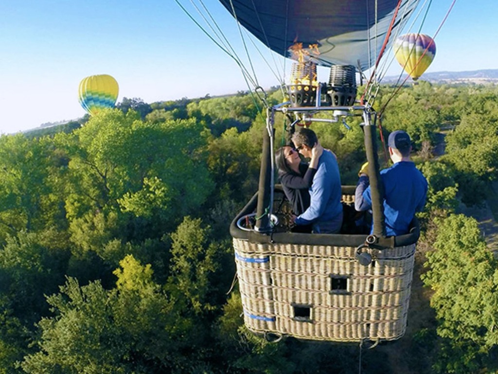 Couple kissing in hot air balloon over vineyards, romantic Napa Valley date experience near SF