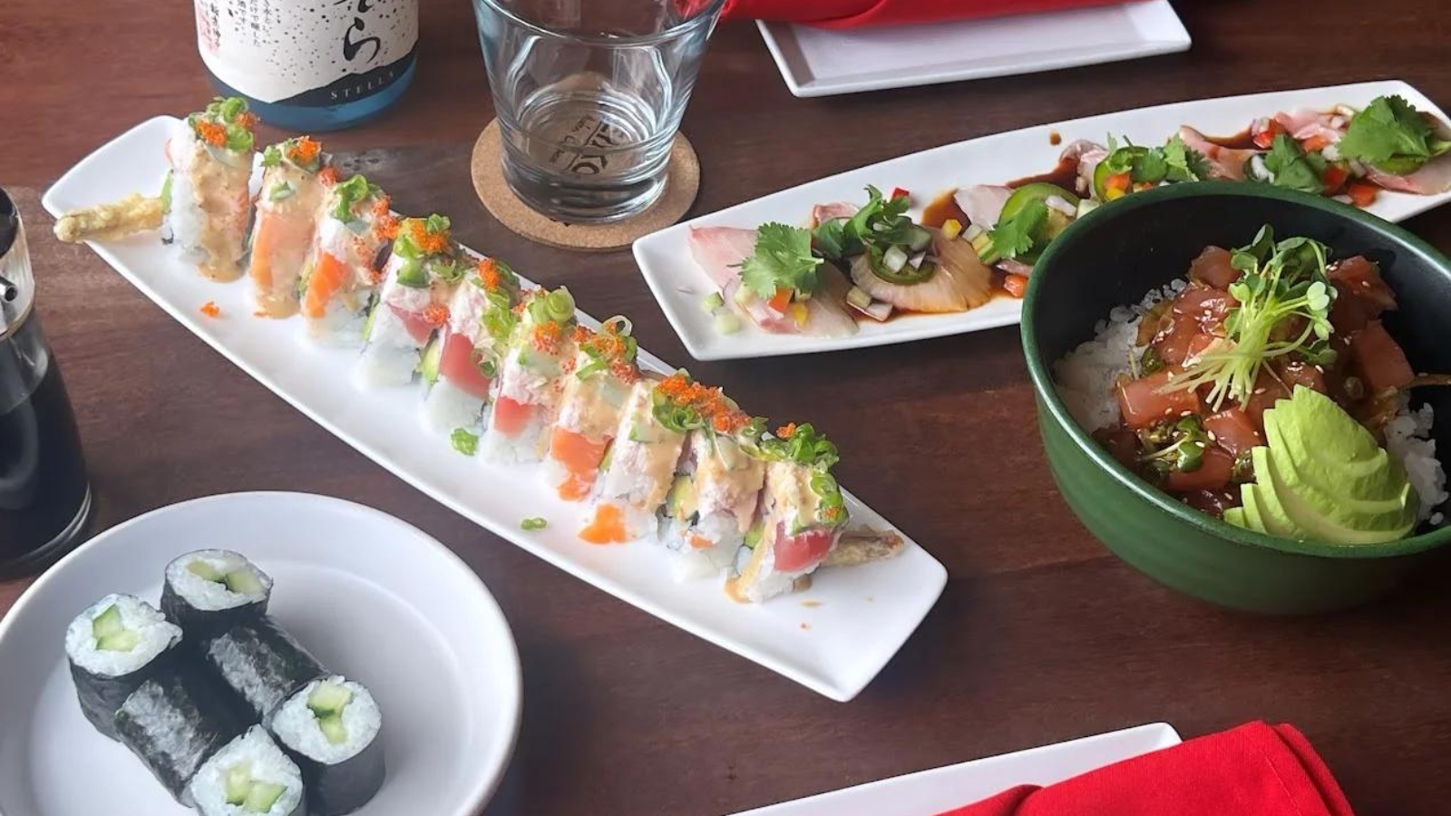 A spread of sushi rolls, poke bowl, and sashimi served on a wooden table, showcasing the fresh menu at a popular Japanese restaurant Napa.